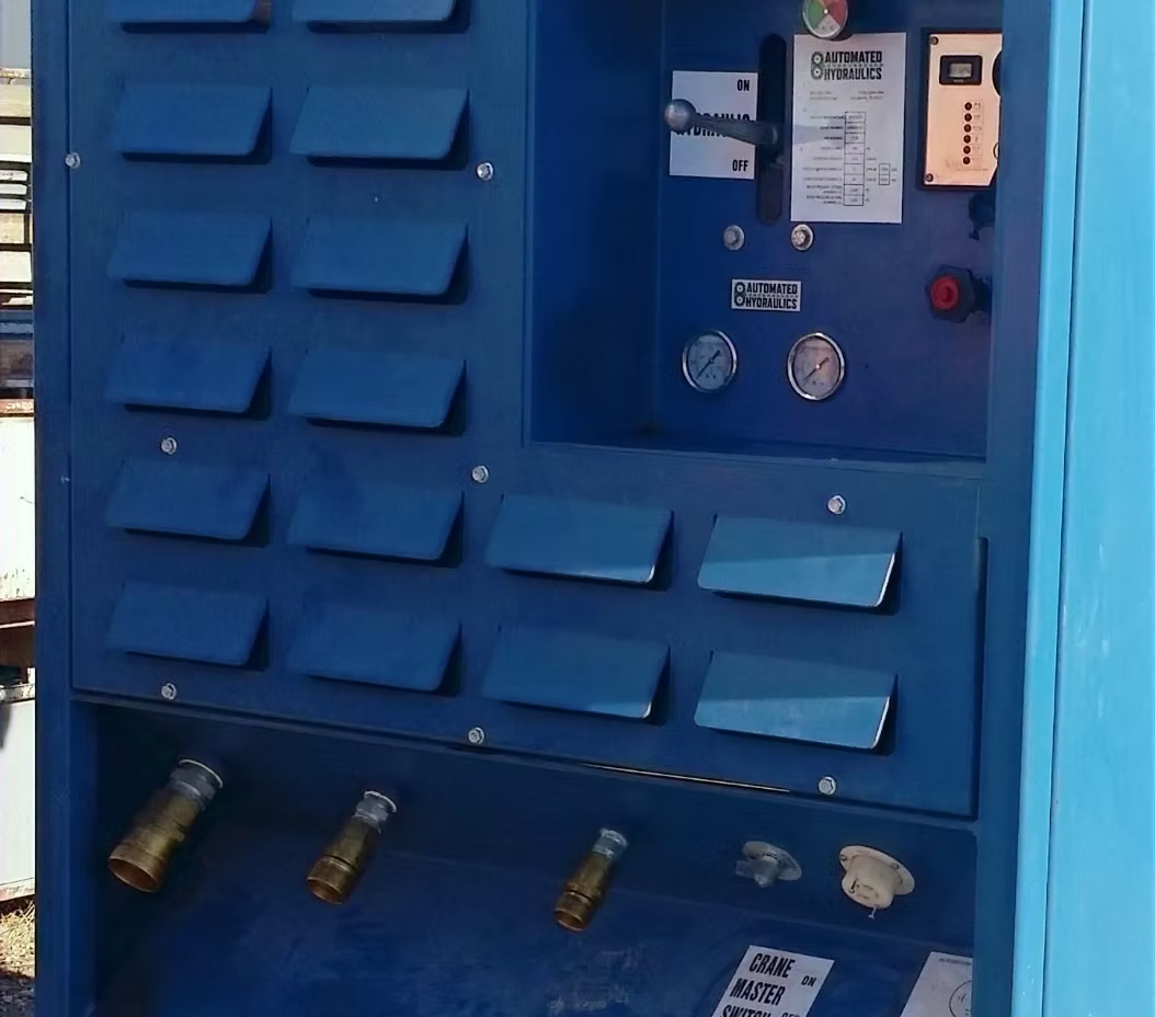 Blue industrial control panel with gauges, switches, and hydraulic system labels